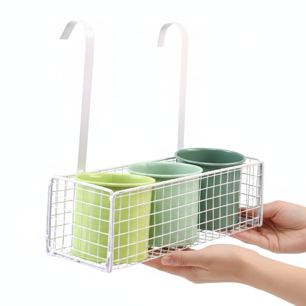 Hängender weißer Drahtkorb aus Metall mit zwei Haken und drei runden Pflanztöpfen in verschiedenen Grüntönen.