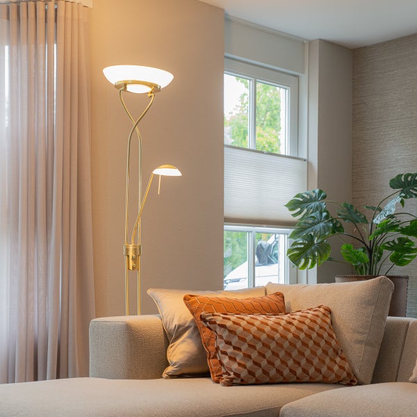 Stehlampe mit Leselampe in einem Wohnzimmer mit Sofa und Zimmerpflanze