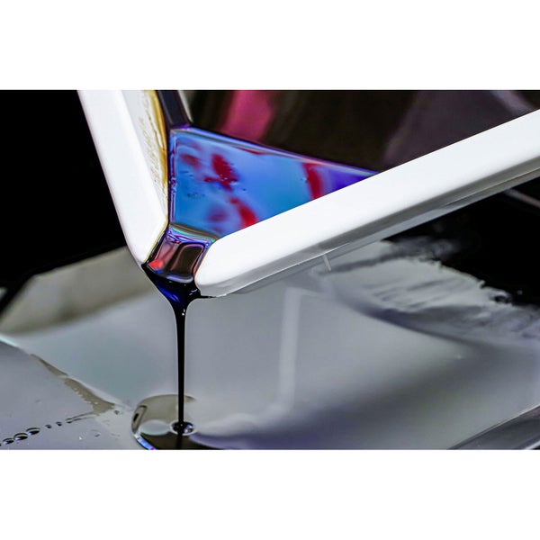 Dunkle Farbe wird aus einer weißen Farbschale in einen Behälter gegossen.