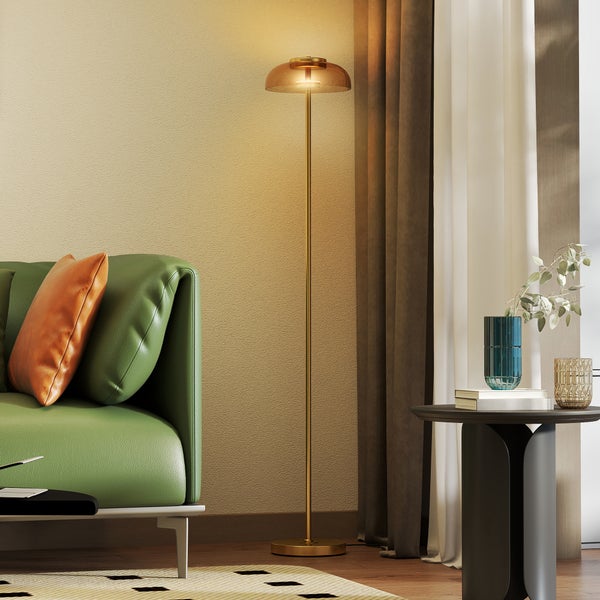 Wohnzimmer mit grünem Sofa, Stehlampe und Beistelltisch.