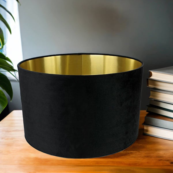 Schwarzer Lampenschirm aus Samt mit goldfarbener Innenseite auf einem Tisch