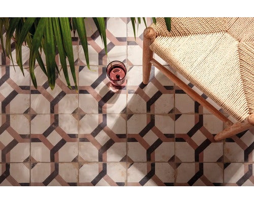 Geometrisch gemusterte Bodenfliesen im mediterranen Stil mit Holzstuhl und Zimmerpflanze.