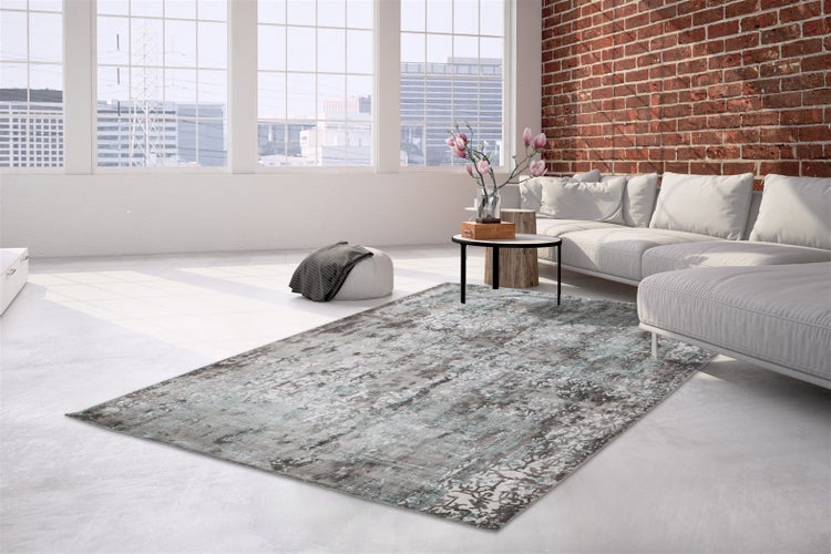 Moderner Wohnzimmerteppich mit abstraktem Muster in einem hellen, industriell eingerichteten Loft mit Backsteinwand und großen Fenstern.
