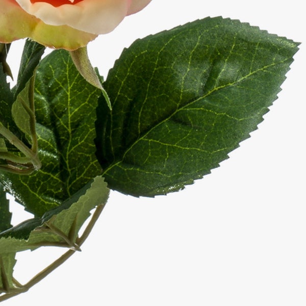 Detailansicht einer künstlichen Rose mit grünen Blättern und einer pfirsichfarbenen Blüte.