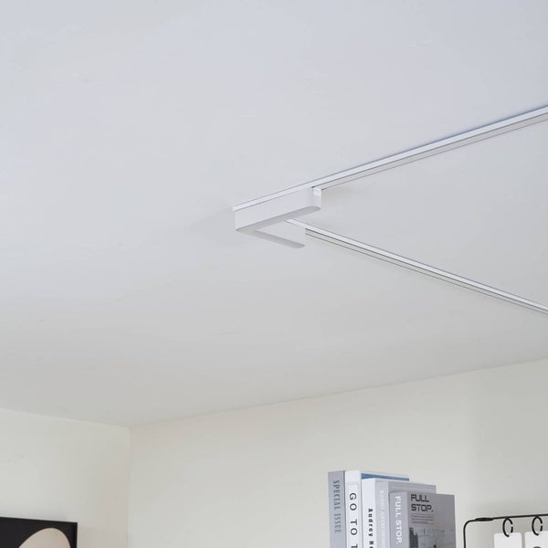 Weißer L-Eckverbinder für ein Schienensystem an einer Decke.