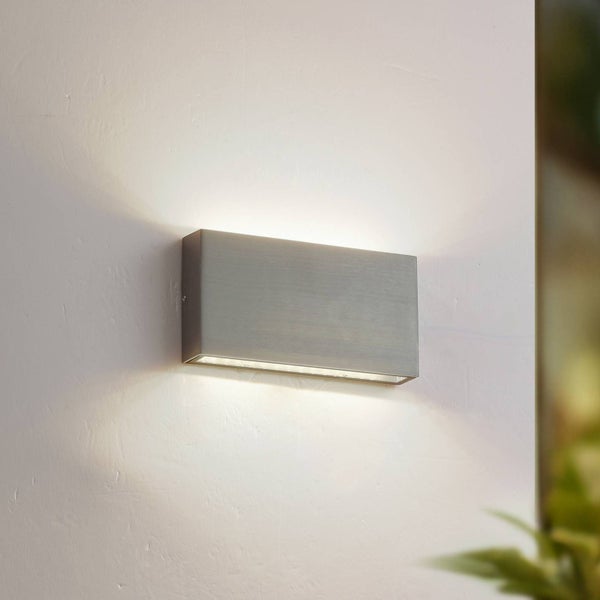 Moderne rechteckige Wandleuchte aus gebürstetem Metall mit Up-and-Down Lichteffekt an einer weißen Wand.