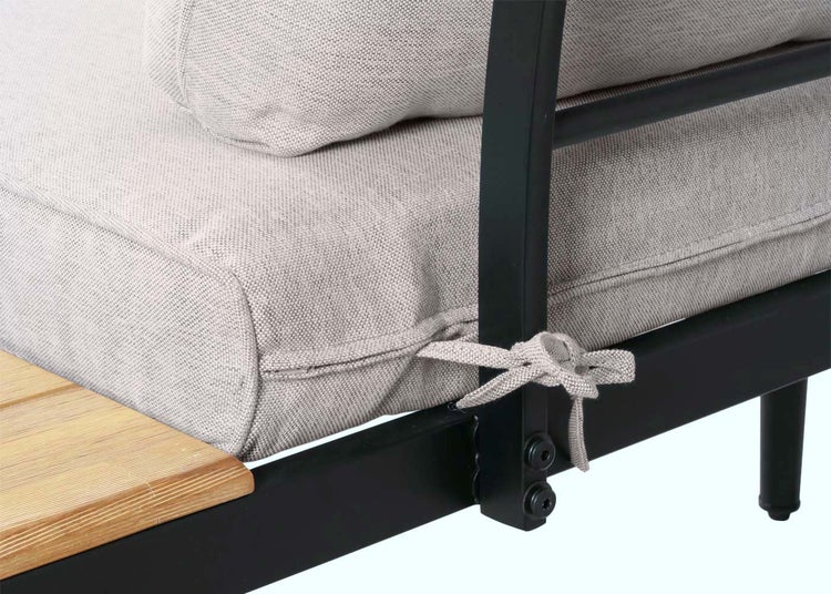Detailansicht eines grauen Sitzkissens mit Befestigungsschleife an einem schwarzen Metallgestell eines Gartenmöbels mit Holzelementen.