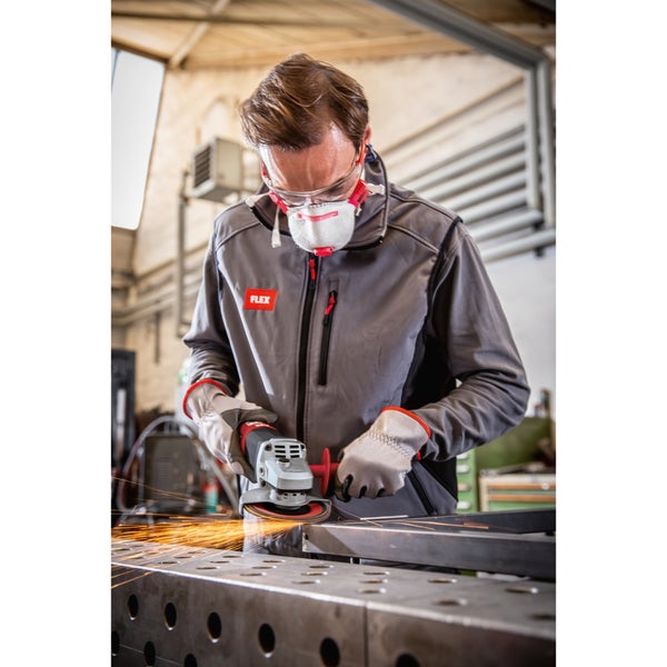 Handwerker mit Schutzausrüstung bei der Arbeit mit einem Winkelschleifer an einem Metallwerkstück in einer Werkstatt.