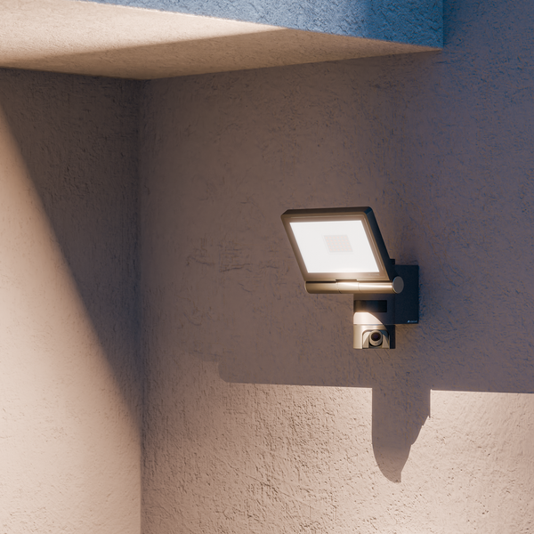 LED-Außenstrahler mit integrierter Kamera und Bewegungsmelder, montiert an einer strukturierten Wand.