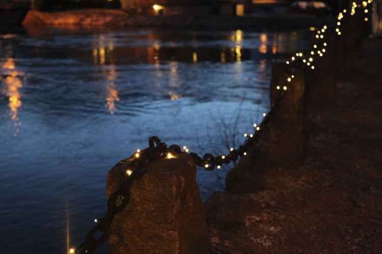 Dekorative Lichterkette entlang einer Metallkette an einem Steinpfosten