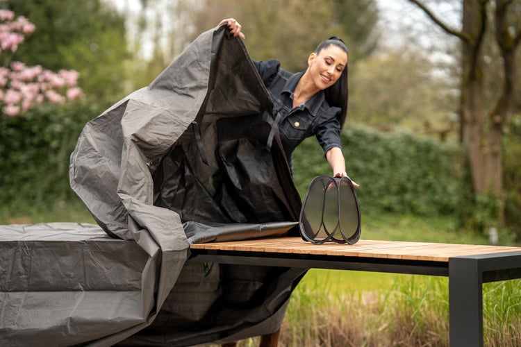 Frau legt eine Schutzhülle über eine Gartensitzgruppe