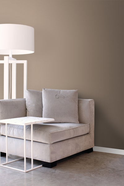 Heller Sessel mit Kissen, Beistelltisch und Stehlampe in einem Wohnraum