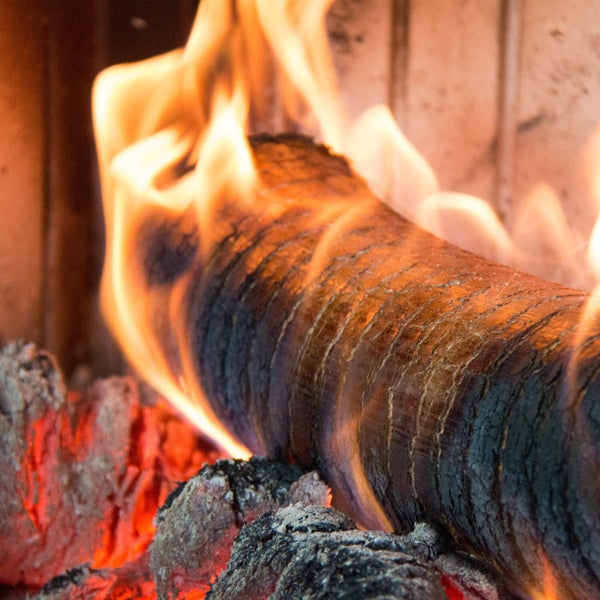 Brennendes Holzscheit in einem Kamin mit glühender Kohle.