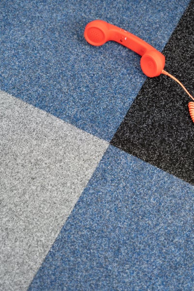 Teppichfliesen in verschiedenen Farben, quadratisch verlegt, strapazierfähige Nadelfilz-Struktur für Büro und Wohnbereich.
