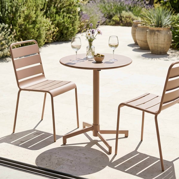 Modernes Bistro-Set aus Metall mit rundem Tisch und zwei Stühlen auf einer hellen Terrasse mit Gartenpflanzen.
