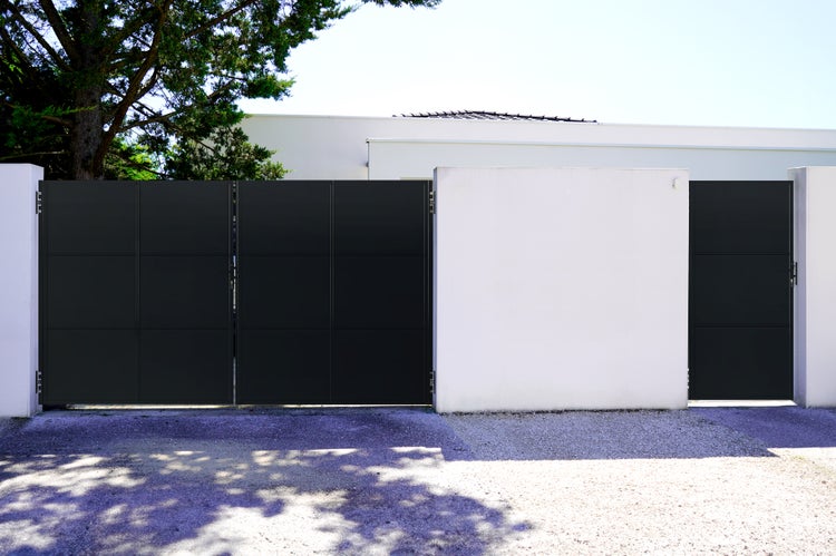 Einfahrtstor mit quadratischen Elementen vor einem weißen Haus