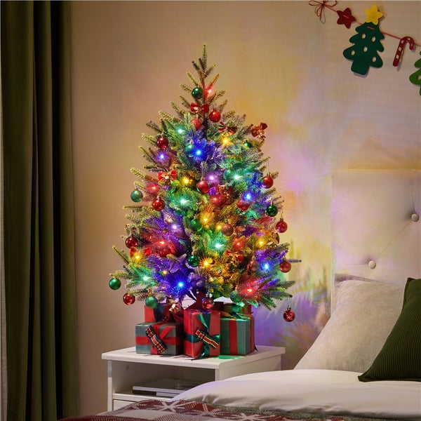 Dekorierter Weihnachtsbaum mit Geschenken auf einem Nachttisch im Schlafzimmer.