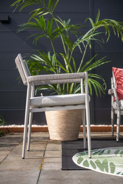 Gartenstuhl mit Metallgestell, seilumwickelten Lehnen und Sitzkissen auf einer hellen Terrasse mit Pflanze und Outdoorteppich.