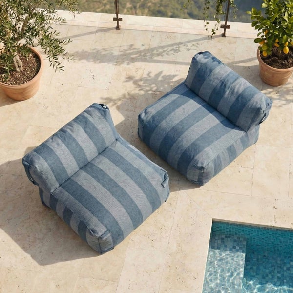 Helle Steinterrasse mit zwei blau gestreiften Outdoor Sitzsäcken neben einem Swimmingpool und Topfpflanzen.