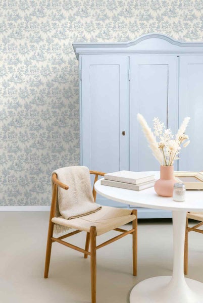 Vliestapete mit Toile-de-Jouy-Muster in einem hellen Raum mit Schrank, rundem Tisch und Holzstuhl im klassischen Stil.