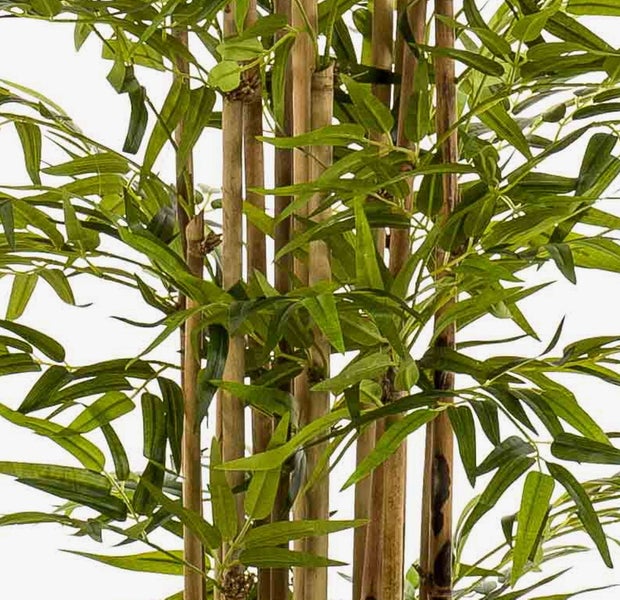 Künstliche Bambuspflanze mit Naturstämmen und dichten grünen Blättern in der Detailansicht.