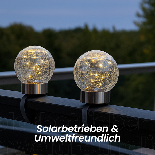 Zwei solargespeiste Kugelleuchten aus Glas und Metall auf einem Geländer