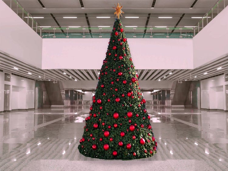 Großer künstlicher Weihnachtsbaum in einem modernen Innenraum dekoriert mit Kugeln und einer Sternspitze.