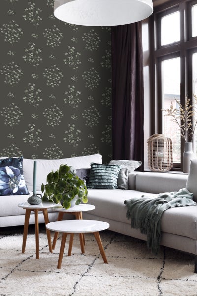 Wohnzimmer mit gemusterter Tapete, Sofa, Teppich und Beistelltischen