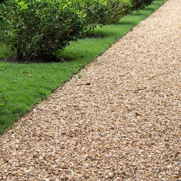 Gartengestaltung mit einem Kiesweg entlang einer grünen Hecke und einer Rasenfläche für eine natürliche Gartenlandschaft.