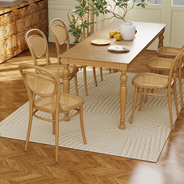 Esstisch aus Holz mit sechs Stühlen mit Wiener Geflecht, platziert auf einem gemusterten Teppich über Parkettboden in Fischgrätoptik.