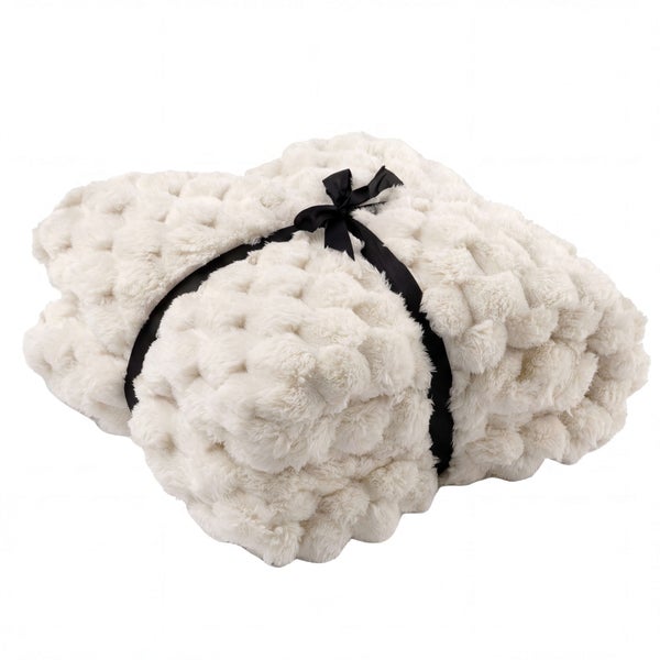 Cremeweiße, flauschige Wohndecke mit Noppenstruktur, gefaltet und mit einer schwarzen Schleife gebunden.