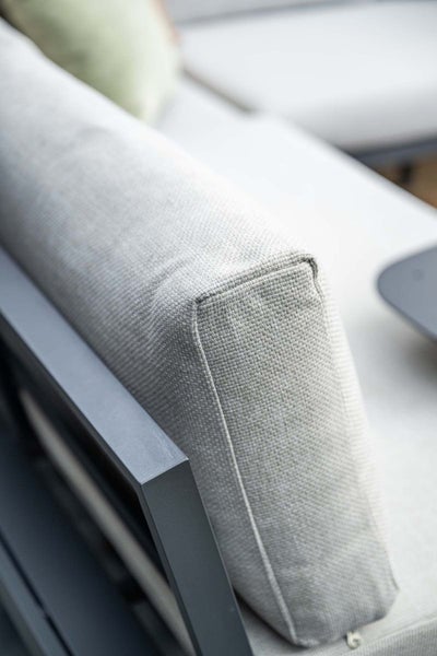 Detailaufnahme eines strukturierten Stoffkissens auf einem Metallrahmen eines Lounge-Gartenmöbels.