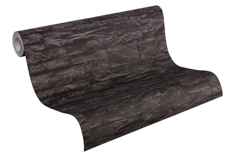 Mann sitzt auf Kommode und spielt Gitarre vor Wandverkleidung in Steinoptik