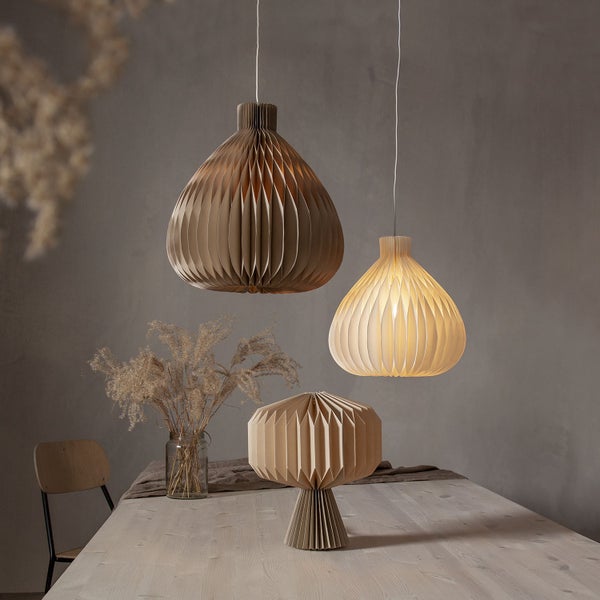 Szene mit zwei Pendelleuchten und einer Tischleuchte aus Papier auf einem Esstisch.