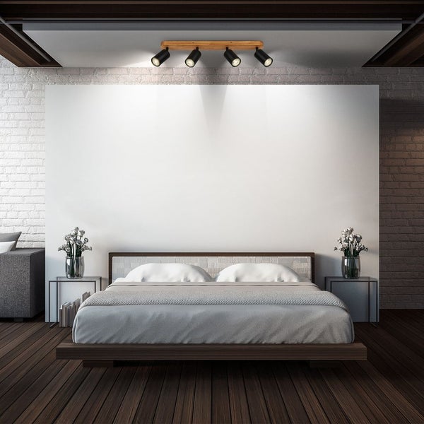 Helles Schlafzimmer mit vierflammiger Deckenleuchte aus Holz und Metall, Doppelbett und Nachttischen vor einer Ziegelwand.