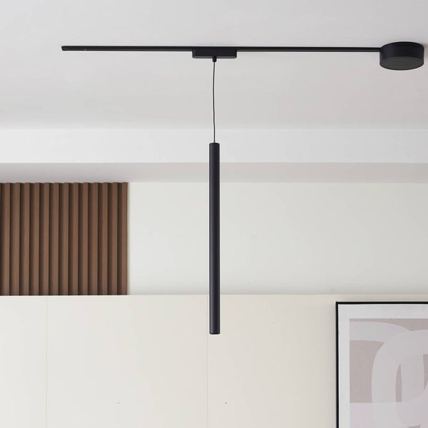 Moderne schwarze zylindrische Pendelleuchte an einer Deckenschiene in einem hellen Raum mit Holzpaneelen.