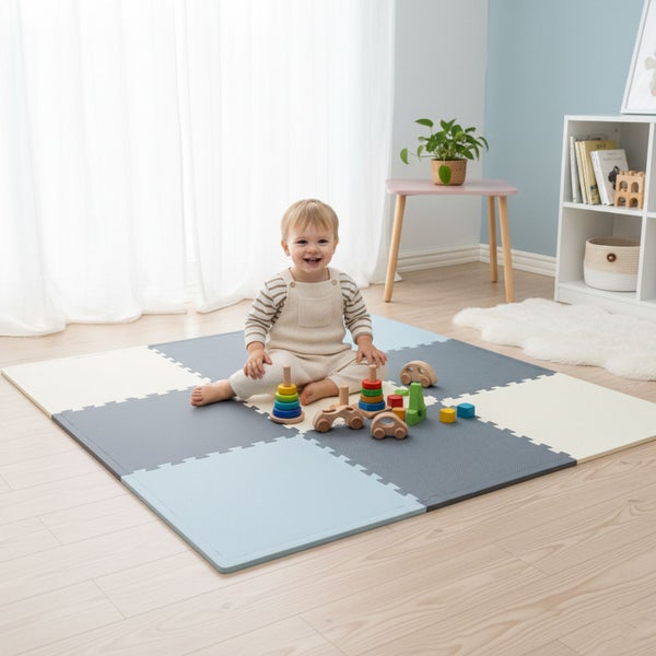 Kleinkind sitzt auf einer Puzzle-Spielmatte aus Schaumstoff mit ineinandergreifenden Quadraten in einem hellen Kinderzimmer mit Holzspielzeug.