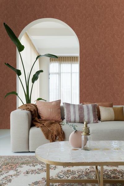 Wohnzimmer mit gemusterter Tapete, Sofa, Kissen, Zimmerpflanze und Couchtisch