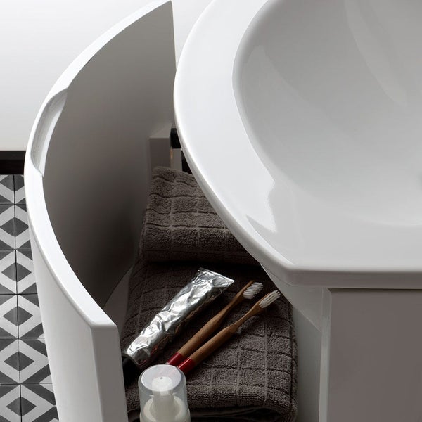 Detailansicht eines Waschbeckens mit Unterschrank, Handtüchern, Zahnbürsten und Zahnpasta