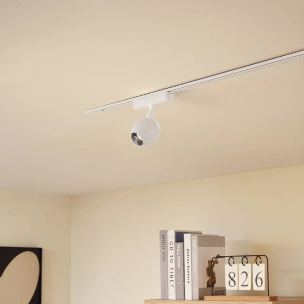 Weißer Schienenstrahler an einer Deckenschiene in einem hellen, organisierten Raum mit Büchern.