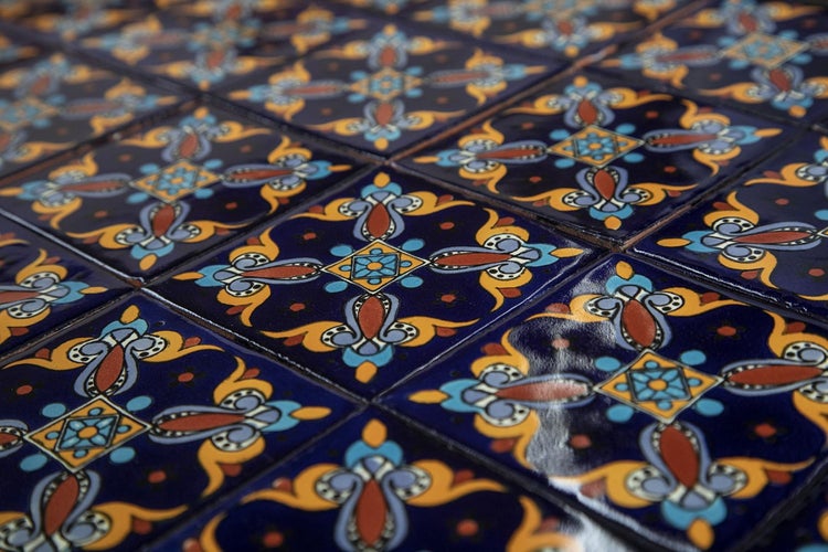 Nahaufnahme von quadratischen, dunkelblauen Fliesen mit floralem Muster