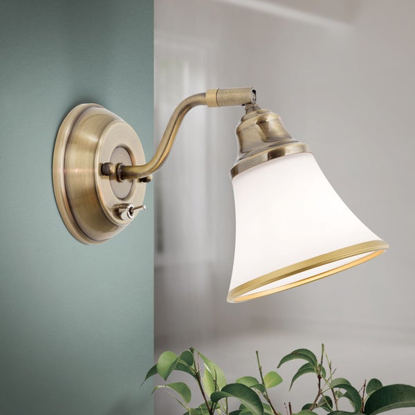 Wandleuchte im Vintage Stil aus Metall in Messingoptik mit einem konischen Glasschirm und integriertem Kippschalter.