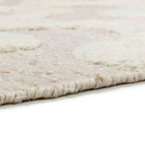 Nahaufnahme eines hellen, gewebten Teppichs mit strukturierter Oberfläche und geketteltem Rand.