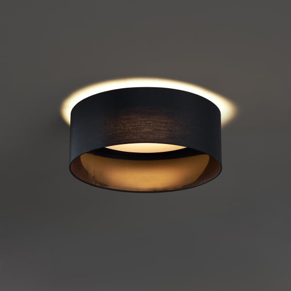 Runde Deckenleuchte mit Stoffschirm in Schwarz und Gold, beleuchtet mit indirektem Lichteffekt an der Decke.