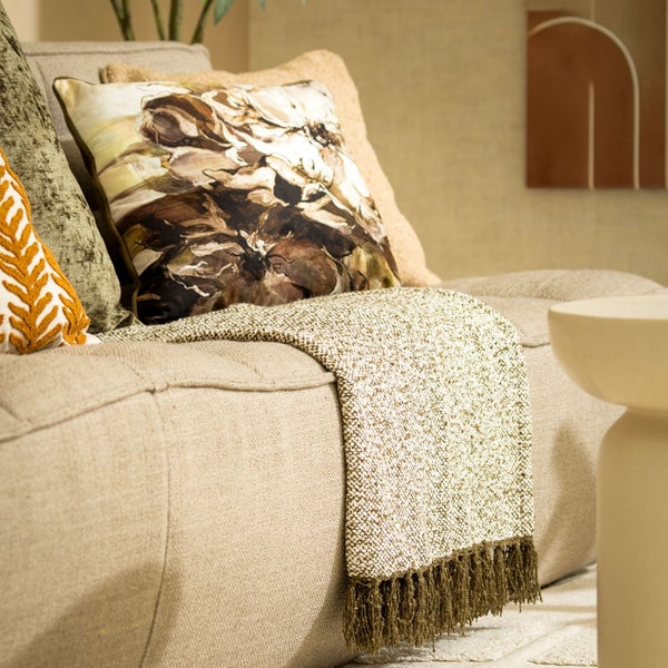 Nahaufnahme eines Sofas mit Zierkissen und einer Decke mit Fransen