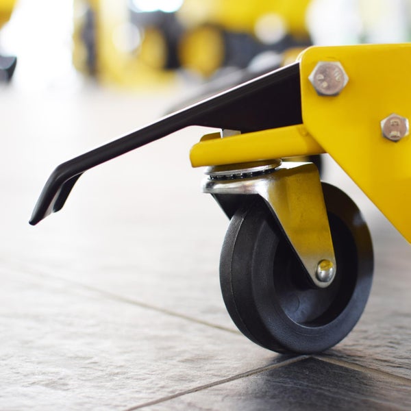 Detailaufnahme einer Transportrolle an einem gelben Werkstattwagen.