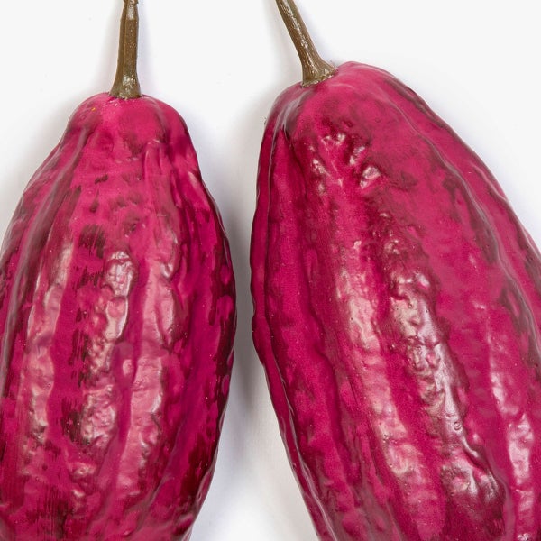 Künstliche Kakaofrüchte in Pink mit strukturierter Oberfläche und braunem Stiel.