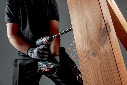 Eine Person bohrt mit einem Akku-Bohrschrauber in ein Holzstück.