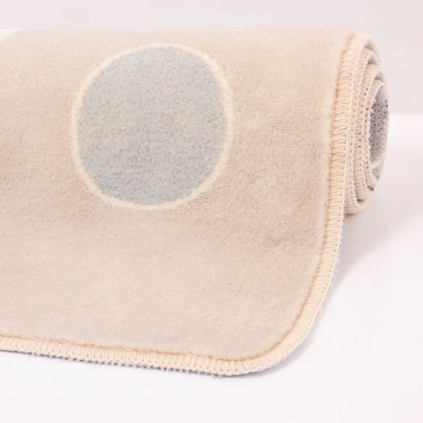 Weicher Teppich mit kreisförmigem Muster und gekettelter Kante, teilweise zusammengerollt.