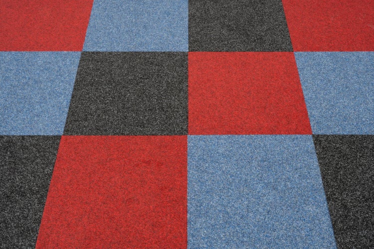 Quadratische Bodenfliesen in Rot, Blau und Schwarz mit körniger Textur, verlegt in einem Karomuster.